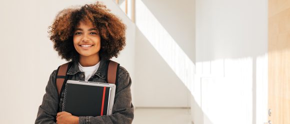 Student is holding book and laptop