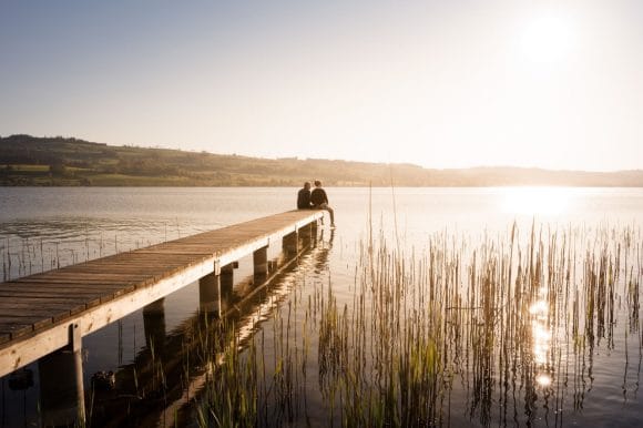 Casal sentado em um píer junto ao lago