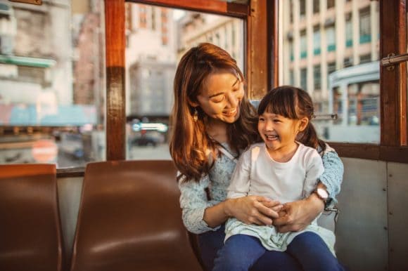 Mother playing with daughter while riding on tram