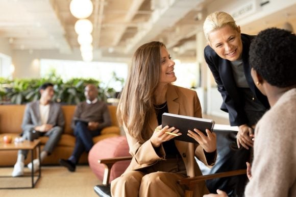 Three people discussing post-it notes on pane