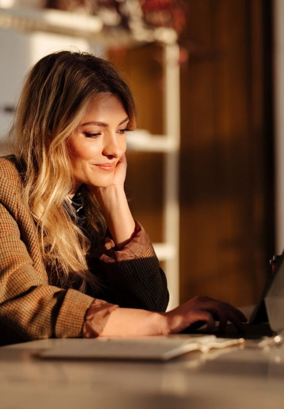 Woman sitting near a desk with laptop and working