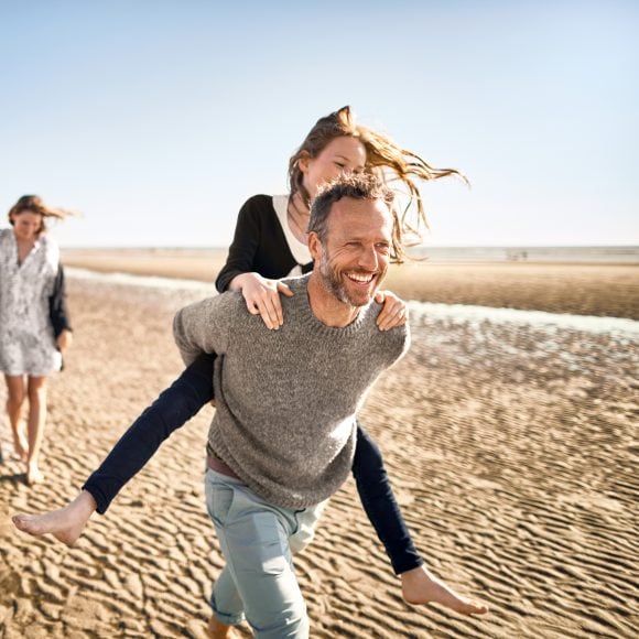 Family with three generations walking on the beach.