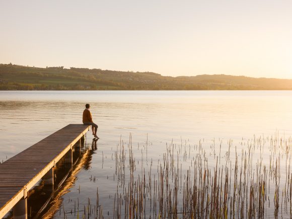 Woman sitting on pier at lake