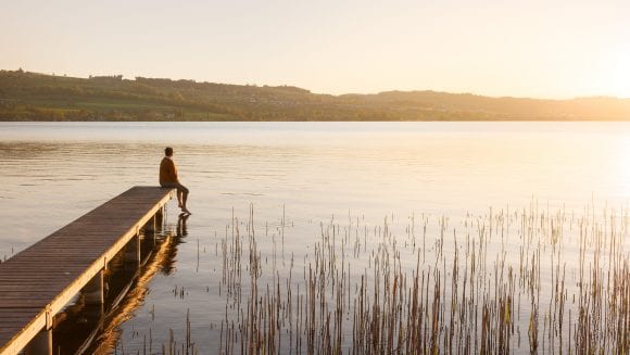 Woman sitting on pier at lake