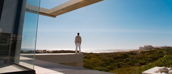 Man standing on an edge of a house looking at the sky