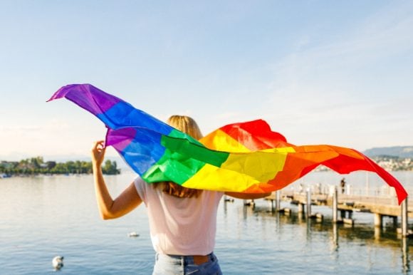  Woman standing at Lake Zurich holding pride flag