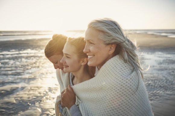 Mother and two children wrapped in blanket on beach