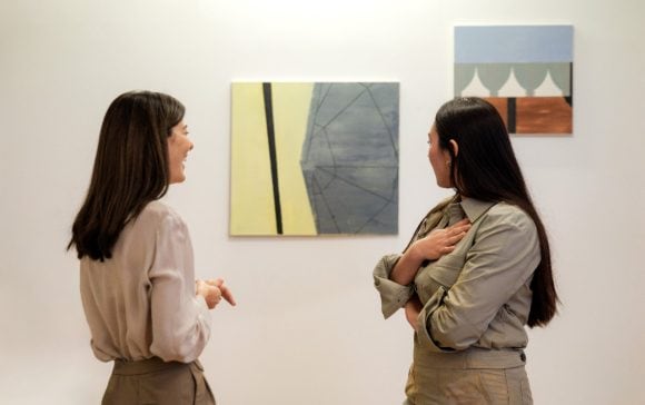 Collector and artist discussing paintings in gallery