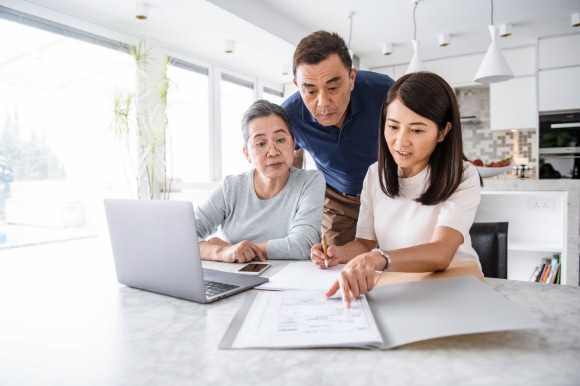 Father daughter and grandmother sitting next to a laptop