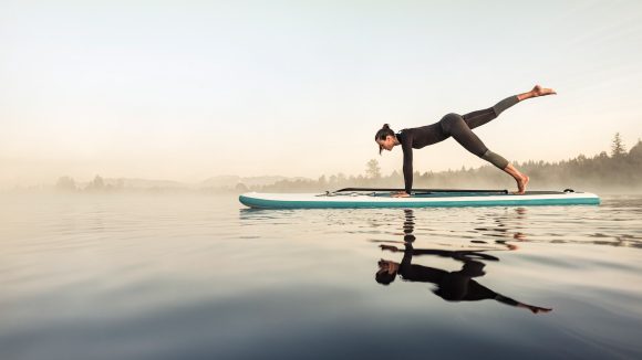 Woman doing yoga on surf board