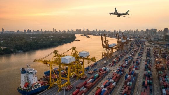 Airplane flying over container cargo terminal