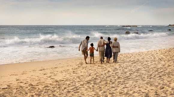 Blended family walking on a beach with waves in the background