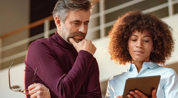 Colleagues viewing tablet in office