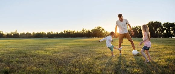 Father playing soccer with children