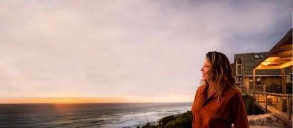 Woman viewing ocean outside beachfront home at sunset