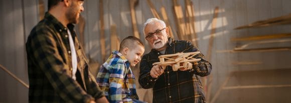 Grandfather and father with a young boy and holding a wooden model airplane