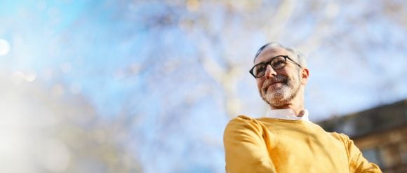 Smiling mature man with glasses, blue sky background