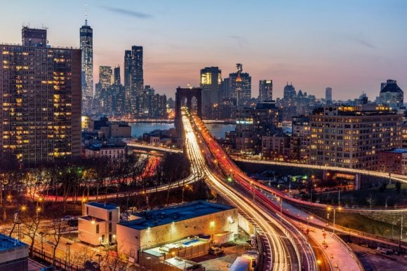 Traffic flowing in and out of New York City over the Brooklyn Bridge at dusk.