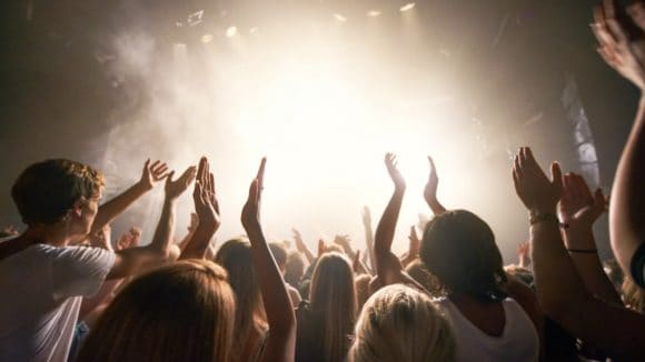 Teenagers clapping in front of a stage.