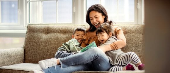 Mother reading to kids on the couch.