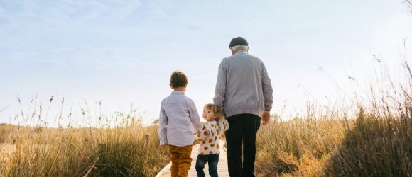 Grandfather walking with grandchildren on a boardwalk