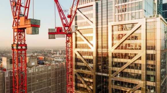 Construction cranes in front of skyscraper