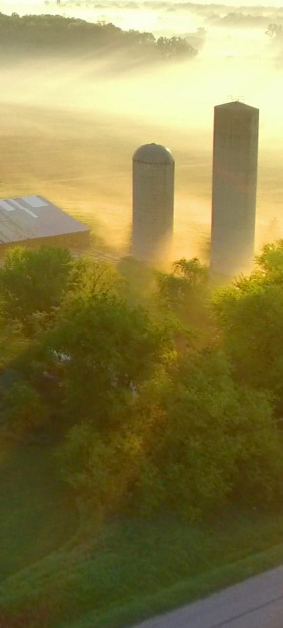 Freight train crossing misty farm landscape