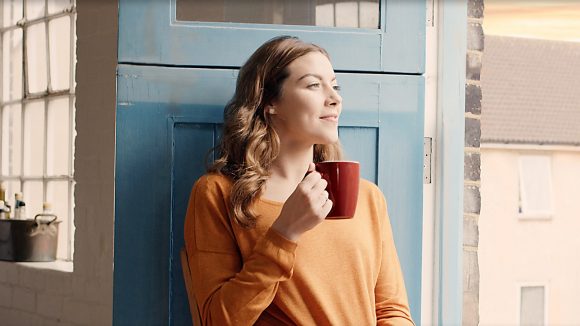 Woman relaxing with a cup of coffee on her balcony